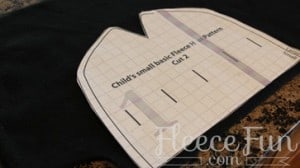 Preparing fleece fabric by cutting and pinning ladybug hat pattern pieces