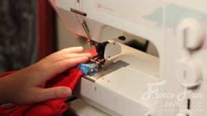sewing the straps to the cape. I love this cute easy superhero cape DIY! It goes around the arms and not the neck for safe play - plus you can turn it around to be a blanket for baby! Easy sewing idea.