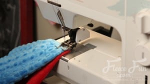 completing the superhero cape. I love this cute easy superhero cape DIY! It goes around the arms and not the neck for safe play - plus you can turn it around to be a blanket for baby! Easy sewing idea.