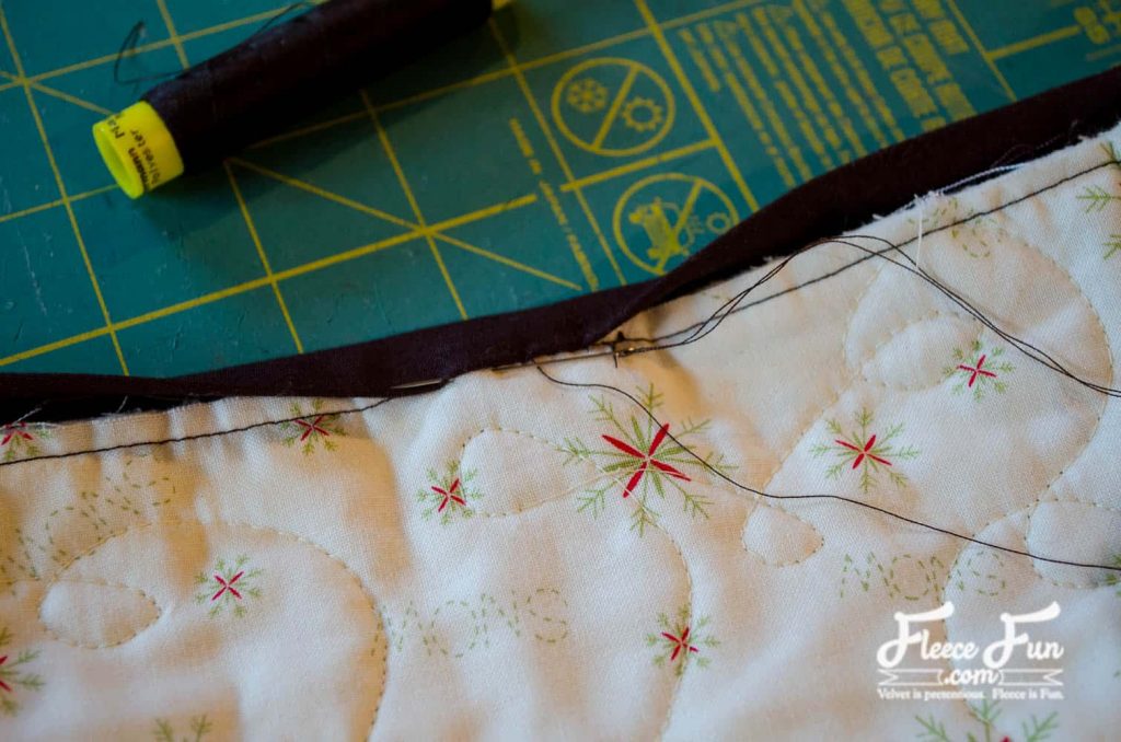 Binding being sewn on the edges of a handmade quilted table runner with fleecefun free instructions