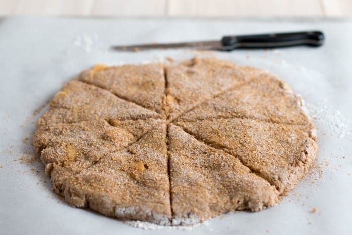 Cutting into wedges. Enjoy Cinnamon Apple Scones with this free recipe, a cozy autumn treat perfect for breakfast, brunch, or sharing warm with friends.