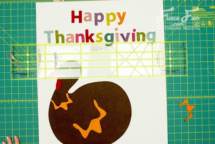 Gluing turkey elements into place for Pin the Tail on the Turkey with FleeceFun's free tutorial.