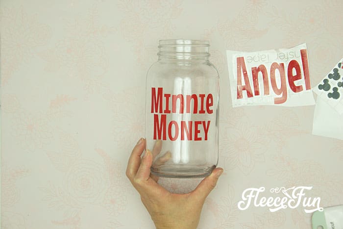 Attaching vinyl designs to a Disney vacation fund jar featuring fleecefun and free template and tutorial