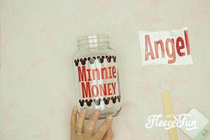 Custom vinyl design being added to a DIY Disney savings jar with fleecefun and free template and tutorial