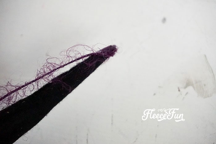 Affixing one end of the purple yarn.