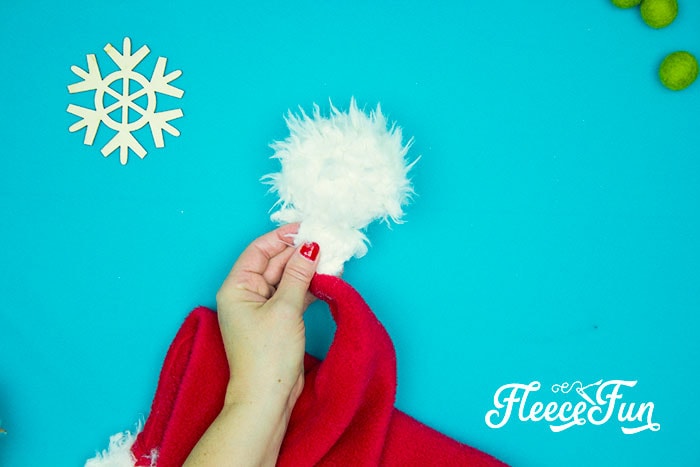 Completing the Santa hat by attaching the pom pom with fleecefun’s free pattern and tutorial