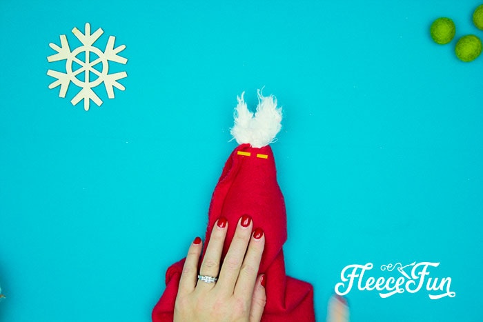 Adding the final touch: attaching the pom pom to the Santa hat using fleecefun’s tutorial