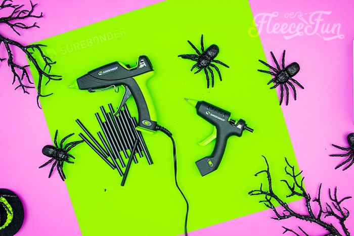 glue gun and glue sticks stitting on a mat. This DIY Mini Witch Hat is no sew and comes with a free PDF pattern and SVG template to make it a breeze! 3 mini sizes so you can make the perfect hat!