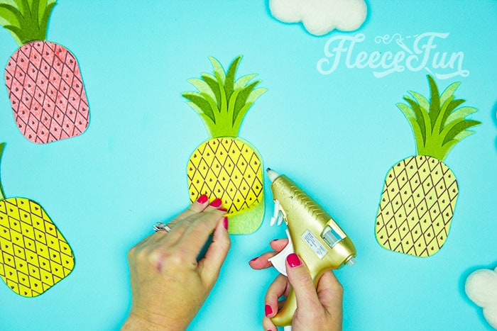 gluing the last item on. This DIY Pineapple décor is easy to make and has many possibilities! Use the free files to make anything from a cute shirt using HTV to a pillow using fabric.  There is something magical about pineapples.  They brings feeling of warmth, vacation and fun!