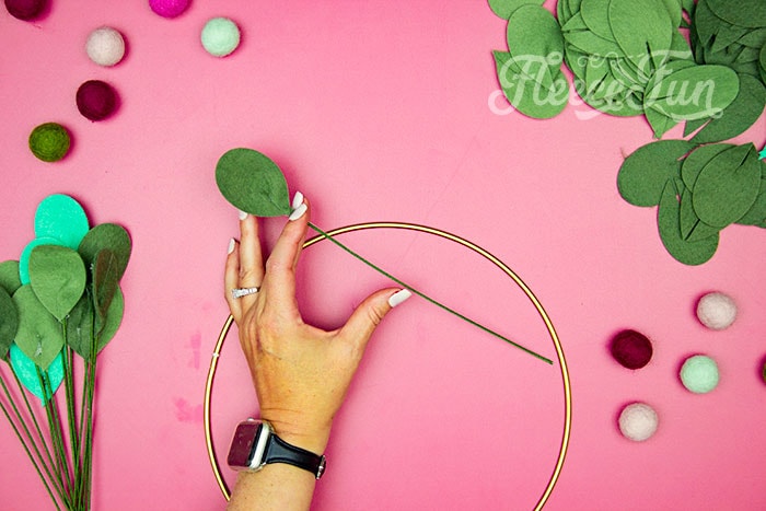 adding wire and leaves to wreath hoop. This modern Christmas Wreath DIY (made from felt) is a whimsical addition to your holiday décor. With a few items you can make this festive wreath. Because of the way it's constructed no two are alike. Make it as full or as thin as your taste's desire. Because it's made from felt, this wreath can be made in an array of colors to suit your style.