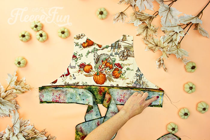 add these pieces to the bodice. Take one wait tie - placing the side that is not finished on the waist piece - center it and sew on using a .25 inch seam allowance.