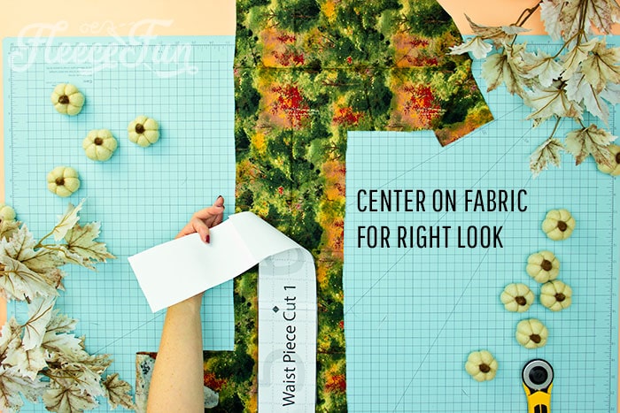 Picture of waist pattern being cut out and how to center on fabric for correct look. This Free apron pattern and tutorial includes a pdf pattern and video! Make a vintage style apron that is chic.