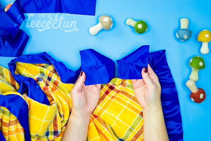 Finishing touches on a satin bound fleece blanket, following fleecefun’s free template