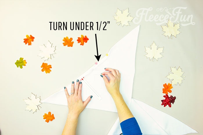 Turn the long diagonal edge under .5 inch. It should fold back to the wrong side of the fabric.