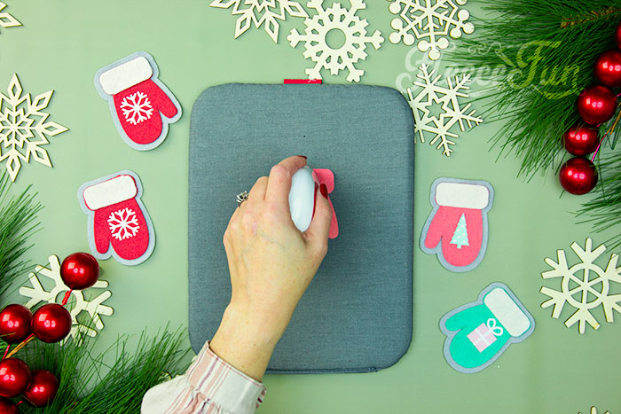 Heat pressing HTV onto a felt mitten ornament using fleecefun's free guide.