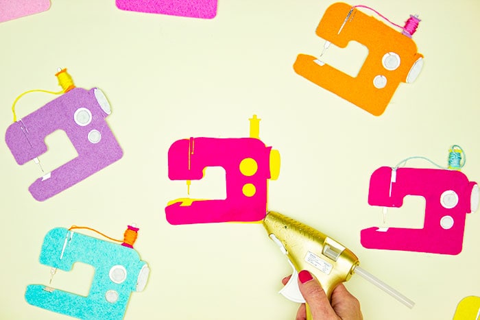 gluing the parts of the sewing room decor. This DIY Sewing Room Décor is a happy addition to your creative space! This cute sewing machine pattern and cut file is perfect for décor, ornaments, garland and more! With a few simple materials you can make this decoration for your sewing studio or a friend! I'm providing you with a PDF plus a JPEG if you want to cut it out using a Cricut.