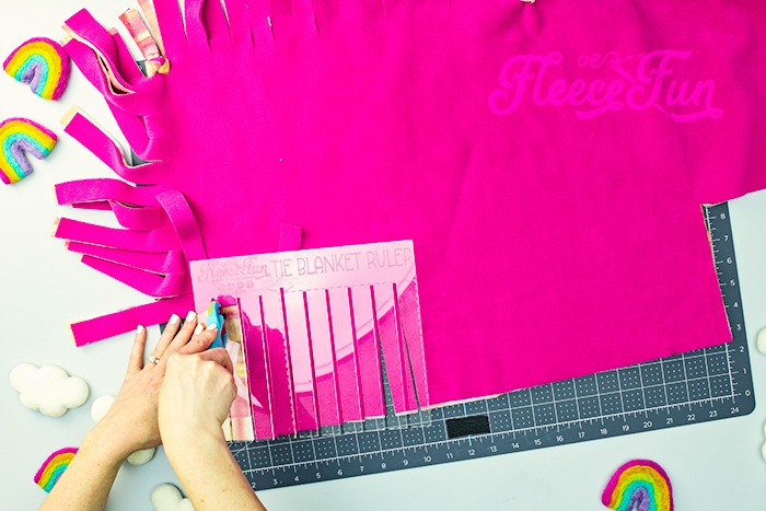 Learn how to use Fleece Fun's Tie Blanket Ruler with this handy tutorial. While tying no sew fleece blankets is easy - CUTTING the thing is and entirely different matter. It takes forever to measure, mark and cut the blanket to get to the tying part of the project! But thanks to this handy Tie Blanket Ruler or Tie Blanket Template (that also happens to be patent pending) you can cut down the cutting and marking to a fraction of the time.