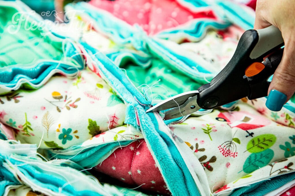 up-close shot of the ragging shears snipping the seam allowance to rag the quilt.