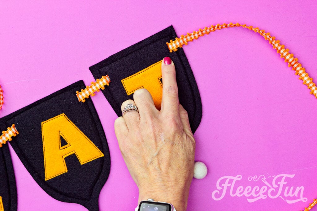 Threading and hanging the DIY Trick or Treat banner using fleecefun’s free template and tutorial.