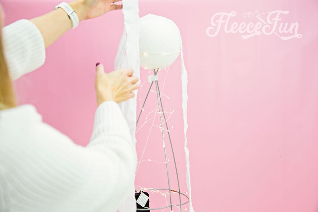 Draping fabric over the tomato cage to create the ghost with fleecefun and free template and tutorial