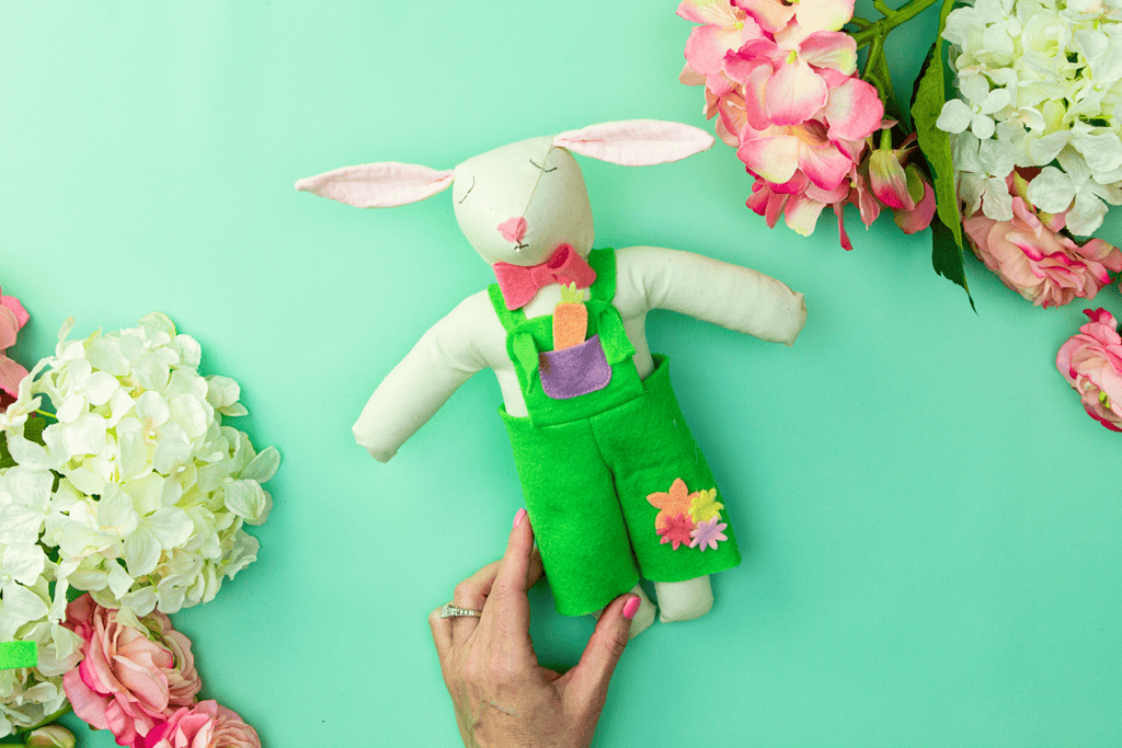 Finished Easter bunny doll wearing felt overalls with a small pocket detail